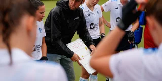 Coach Daan Sabel geeft uitleg aan de speelsters van Tilburg tijdens een rustmoment. 