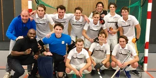 Teamfoto met twee rijen jongens witte tenues. Links staan de twee coaches, Patrick Jeuken en Churandy Martina. 