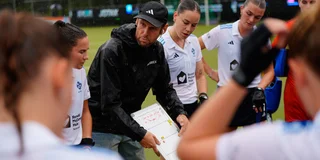 Coach Daan Sabel geeft uitleg aan de speelsters van Tilburg tijdens een rustmoment. 