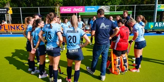 Nijmegen staat na de wedstrijd in een kring met lachende gezichten. Rechts in het rood de nieuwe achternaam op de rug van keepster Nathalie Hessler.