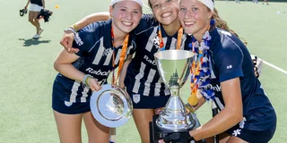 Floortje Lemaire, Suze de Bruin en een derde teamgenoot houden de kampioensschaal en -beker vast. 